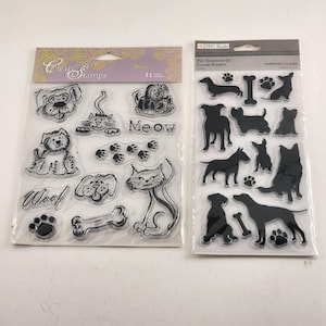 Puede incluir: Dos paquetes de sellos transparentes con siluetas de mascotas. El primer paquete tiene 11 sellos e incluye imágenes de un perro, un gato, huellas de patas y las palabras "Woof" y "Meow". El segundo paquete tiene 11 sellos e incluye imágenes de varias razas de perros en silueta.