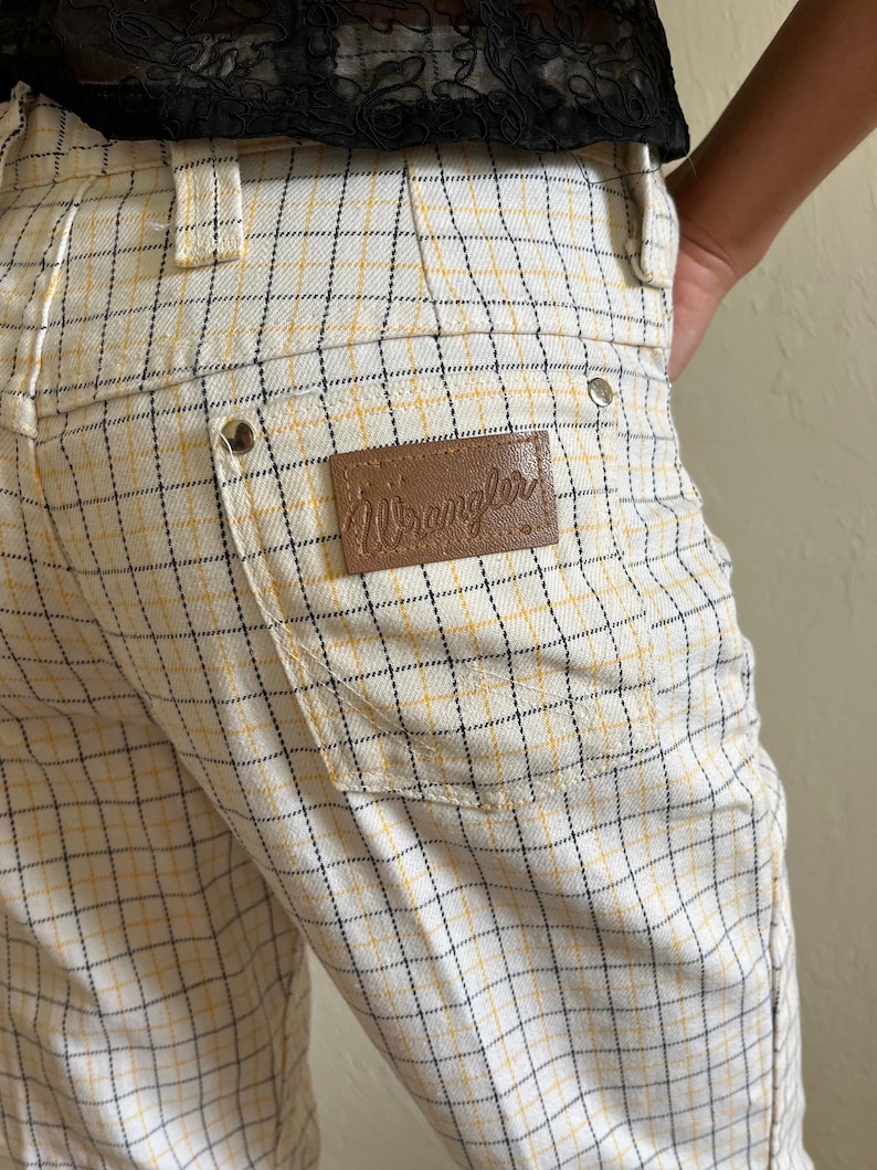 K&ouml;nnte beinhalten: Wei&szlig;e und gelbe karierte Hose mit einem braunen Leder-Wrangler-Etikett.