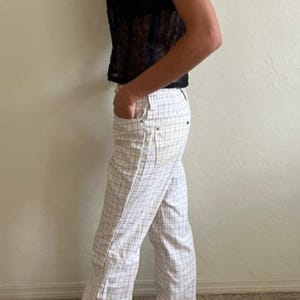 K&ouml;nnte beinhalten: Wei&szlig;e Hose mit einem schwarz-wei&szlig; karierten Muster. Die Hose hat eine weite Beinweite und ist aus einem leichten Stoff gefertigt.