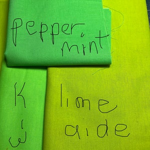 May include: Two pieces of fabric, one green and one yellow-green. The green fabric has the text "pepper mint" written on it. The yellow-green fabric has the text "lime aide" written on it.