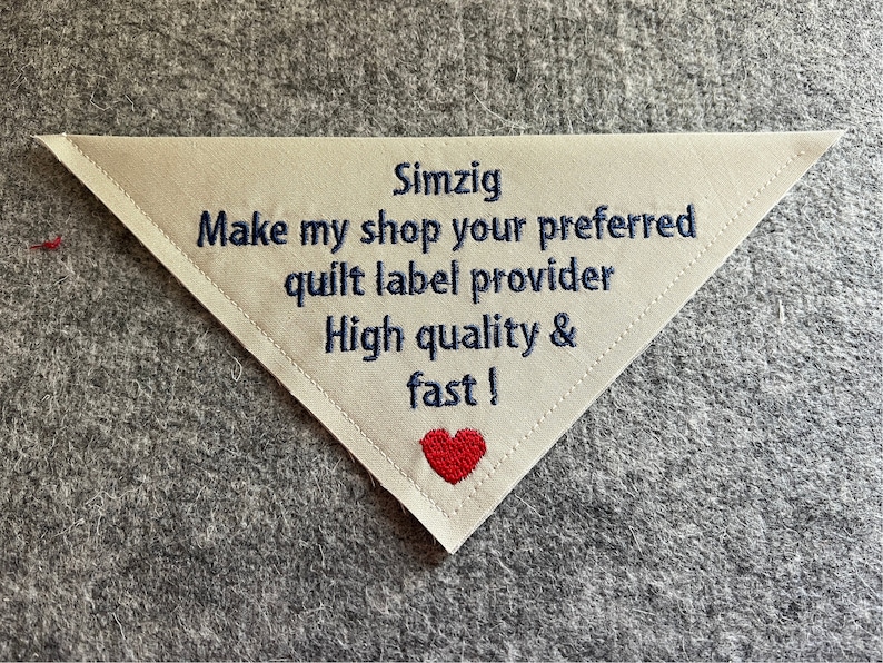 May include: White triangular fabric label with blue embroidered text that reads "Simzig Make my shop your preferred quilt label provider High quality & fast!" with a red heart at the bottom.