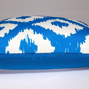 May include: A blue and white patterned throw pillow with a solid blue back. The pillow is made of a soft, comfortable fabric and has a zipper closure.