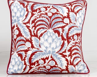 May include: A red and blue patterned throw pillow with a floral design. The pillow has a red border and a white background.