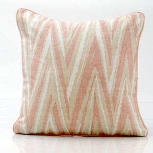 May include: A pink and cream patterned throw pillow with a subtle zigzag design. The pillow has a pink border and is made of a soft, textured fabric.