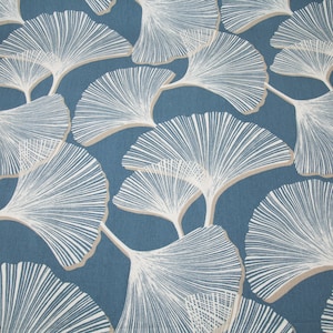 Puede incluir: Una tela azul con un patrón de hojas de ginkgo blanco. Las hojas están delineadas en un color marrón claro.