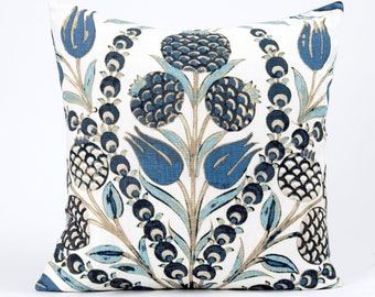 Puede incluir: Una almohada blanca con un patrón floral azul y marrón. El patrón presenta flores, hojas y bayas estilizadas.