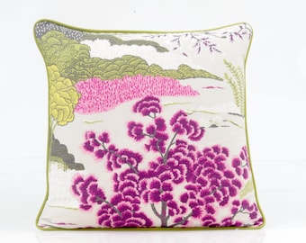 Può includere: Un cuscino decorativo con un bordo verde e uno sfondo bianco con un motivo floreale rosa e viola.