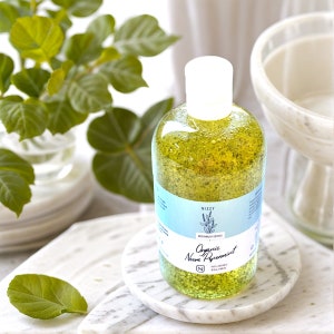 May include: A clear glass bottle with a green liquid and a white label that says "Nizzy Bodywash Series Organic Neem Peppermint 100% Organic"