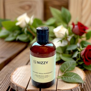 May include: A brown bottle of organic neem peppermint hand and body wash with a white label that says "NIZZY" and "ORGANIC NEEM PEPPERMINT HAND AND BODY WASH Neem, Peppermint, Olive Oil 8 fl. oz. (240 mL)".