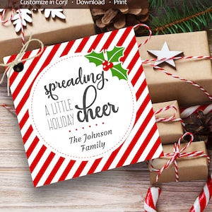 May include: Red and white striped gift tag with a circle in the centre. The circle has a holly sprig with red berries and the text "spreading a little holiday cheer" in black. Below the circle is the text "The Johnson Family".
