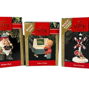 May include: Three boxed Hallmark Keepsake Christmas ornaments with blinking lights. The ornaments feature a gnome with a camera, a child writing a letter to Santa on a computer, and a deer crossing sign with a squirrel.