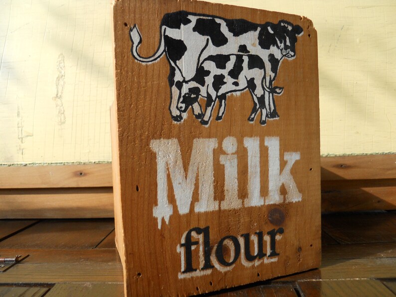 May include: A wooden box with a black and white illustration of two cows and the text "Milk flour" painted on the front.