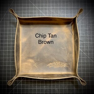Puede incluir: Una bandeja de cuero marr&oacute;n con un dise&ntilde;o de monta&ntilde;a y el texto "Chip Tan Brown" en el centro.