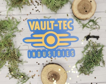 Puede incluir: Una pegatina azul y amarilla de Vault-Tec Industries. La pegatina tiene un fondo azul con texto amarillo y un círculo amarillo. Musgo verde, rodajas de madera y purpurina dorada rodean la pegatina.