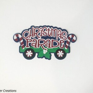 May include: A green, blue, and red Christmas parade sign with candy canes and snowflakes. The sign says "Christmas Parade".