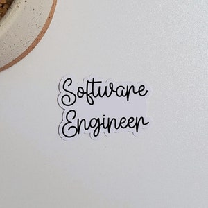 May include: A white sticker with black cursive text that reads "Software Engineer".