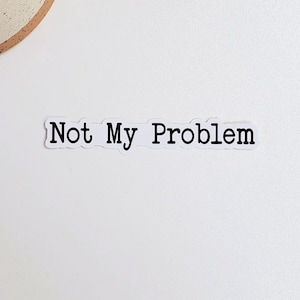 May include: White sticker with the text "Not My Problem" on a white background. A small potted succulent plant is in the upper left corner of the image.