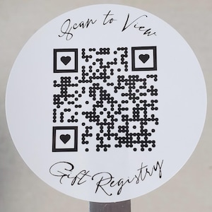 May include: White circular sticker with a black and white QR code and the text "Scan to View Gift Registry".