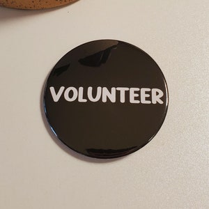May include: A black round button with the word "VOLUNTEER" in white text.