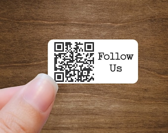 May include: A white sticker with a black QR code and the text "Follow Us" on a wood background.