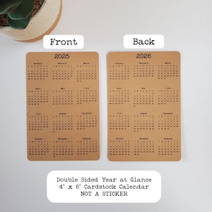 May include: Double-sided year-at-a-glance calendar printed on brown cardstock. The front side shows the year 2025 and the back side shows the year 2026. The calendar is 4 inches by 6 inches and is not a sticker.