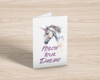 May include: A watercolor painting of a white unicorn head with a purple inscription that reads "Follow Your Dreams".