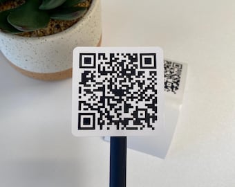 May include: A white square sticker with a black QR code on it. The sticker is attached to a blue pen.