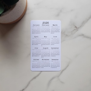 May include: A set of three ceramic mugs with a speckled, matte finish. Each mug features a different color: light blue, cream, and gray. The mugs have a simple, modern design, perfect for coffee or tea.