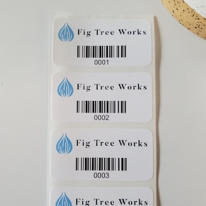 May include: Three white rectangular labels with a blue fig logo and the text "Fig Tree Works". Each label has a black barcode and a number: 0001, 0002, and 0003.