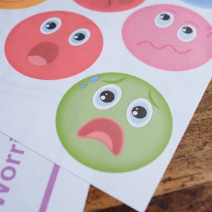 May include: A green cartoon face with a worried expression. The face has large blue eyes, a red mouth, and two small blue drops of sweat above the eyes.