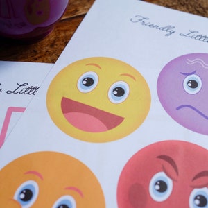 May include: A printable sheet with the text "Friendly Little" at the top. There are four colorful cartoon faces with different expressions. The faces are yellow, orange, red, and purple.