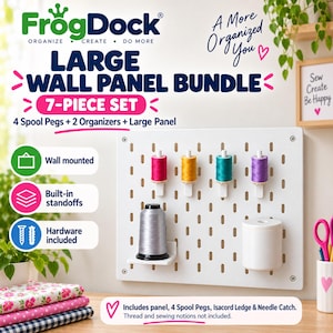May include: A white wall-mounted pegboard organizer set labeled FrogDock Large Wall Panel Bundle 7-Piece Set. It includes a rectangular panel with four colorful thread spool pegs, a small shelf holding a grey thread spool, and a white cylindrical needle catch.