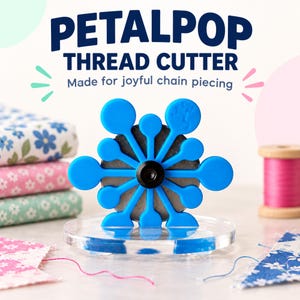 Puede incluir: Un cortahilos Petalpop azul con una cuchilla metálica circular y un tornillo central negro, montado sobre una base circular transparente. El texto PETALPOP THREAD CUTTER Made for joyful chain piecing aparece arriba en letras azul oscuro.