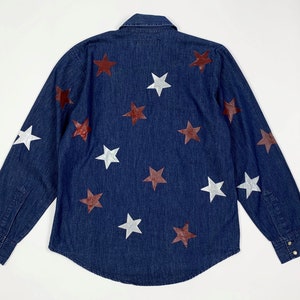 K&ouml;nnte beinhalten: Ein dunkelblaues Jeanshemd mit langen &Auml;rmeln, Knopfleiste und einem Muster aus wei&szlig;en und kastanienbraunen Sternen.
