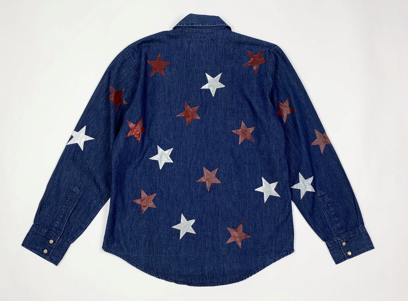 K&ouml;nnte beinhalten: Ein dunkelblaues Jeanshemd mit langen &Auml;rmeln, Knopfleiste und einem Muster aus wei&szlig;en und kastanienbraunen Sternen.