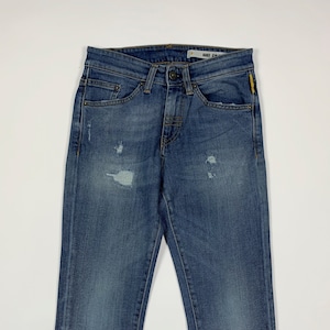 Può includere: Jeans in denim blu con dettagli consumati e un'etichetta gialla con la scritta "MANGO 21" sul retro della cintura.