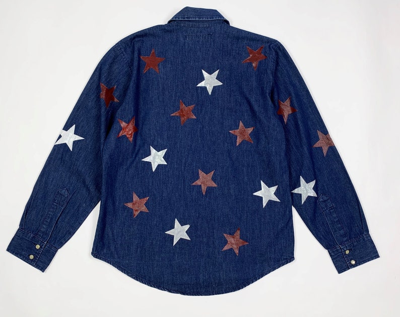 K&ouml;nnte beinhalten: Ein dunkelblaues Jeanshemd mit langen &Auml;rmeln und Knopfleiste. Das Hemd ist mit wei&szlig;en und kastanienbraunen Sternen verziert.