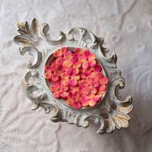 Peut inclure: Un plateau décoratif orné de blanc avec un motif floral. Le plateau est rempli de fleurs en tissu rose et orange.
