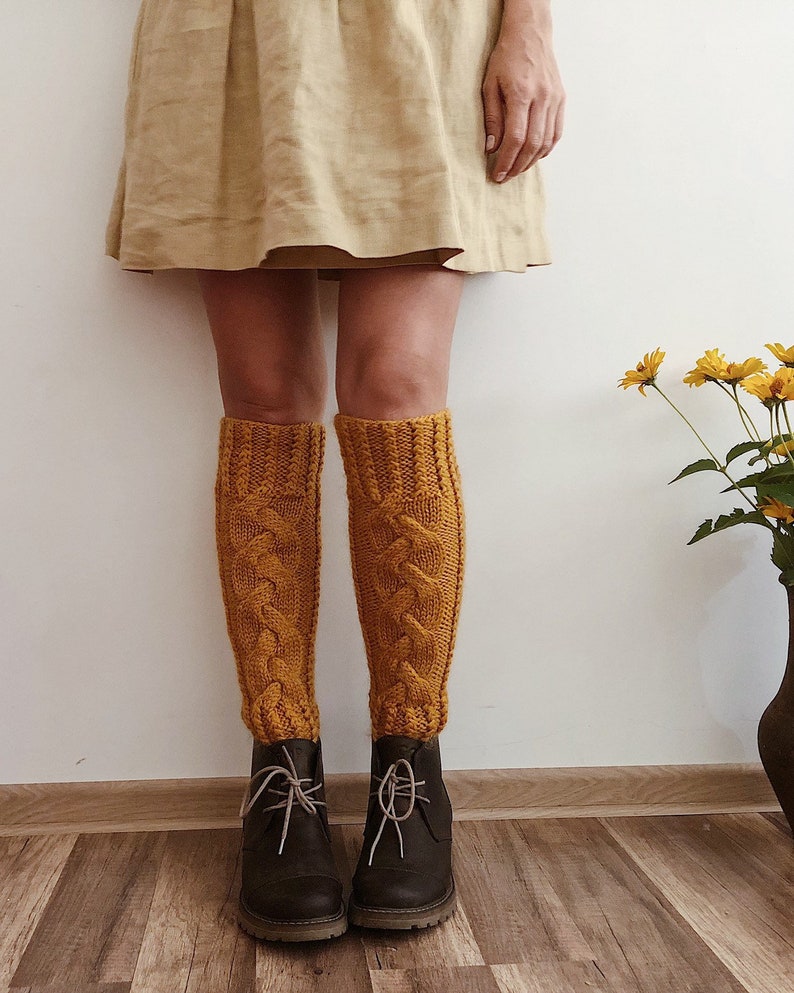 May include: A person wearing a beige skirt and mustard yellow knitted knee-high socks with brown leather boots.