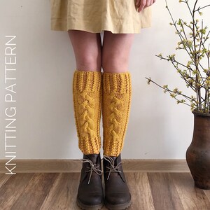 May include: A pair of yellow knitted leg warmers with a cable knit pattern. The leg warmers are worn over brown boots.