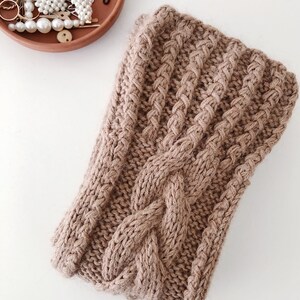 May include: A brown knitted headband with a cable knit pattern.