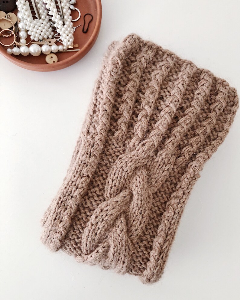 May include: A brown knitted headband with a cable knit pattern.