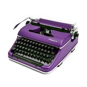 May include: A purple vintage typewriter with black keys and the word "Olympia" printed on the front.