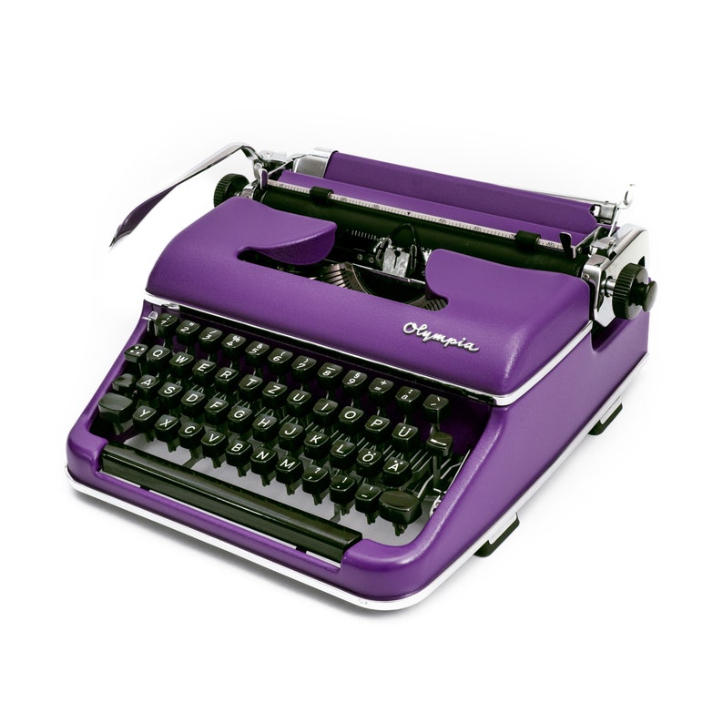 May include: A purple vintage typewriter with black keys and the word "Olympia" printed on the front.