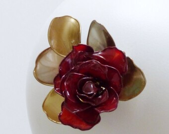 May include: A red rose with gold leaves, a decorative hair clip.