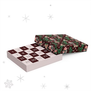 May include: A Christmas advent calendar with a white base and a checkerboard pattern of brown squares with numbers. The lid is open, revealing a festive pattern of green leaves, pink flowers, and gift boxes on a dark red background.