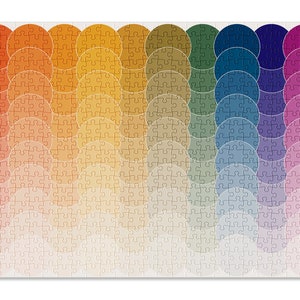 May include: A colorful jigsaw puzzle with a rainbow pattern of overlapping circles. The puzzle pieces are arranged in a wave-like pattern, with the colors transitioning from red to orange, yellow, green, blue, purple, and pink.