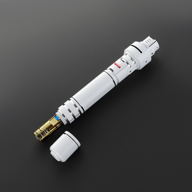 May include: A white and silver handheld device with a red button and a removable end cap. The device is open, revealing a gold-colored interior.