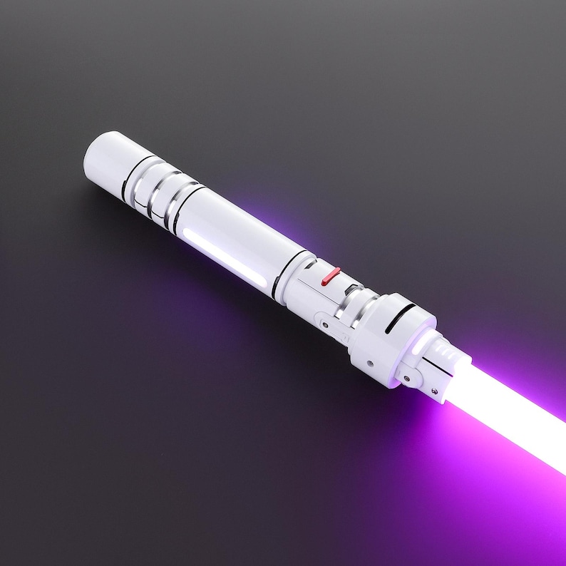 May include: A white lightsaber with a purple blade. The lightsaber has a red button and a silver accent.