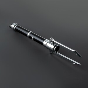 May include: A black and silver multi-pronged tool with a handle. The tool has a sharp point at the end of each prong.